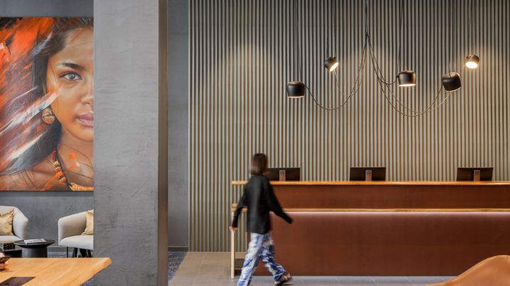 A person walking through a hotel reception area designed in sleet grey and artistic flair